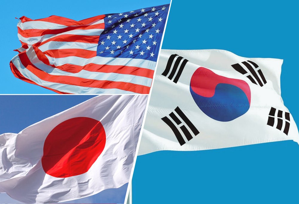 W lewym górnym rogu flaga Stanów Zjednoczonych, w lewym dolnym rogu flaga Japonii, po prawej stronie flaga Korei Południowej