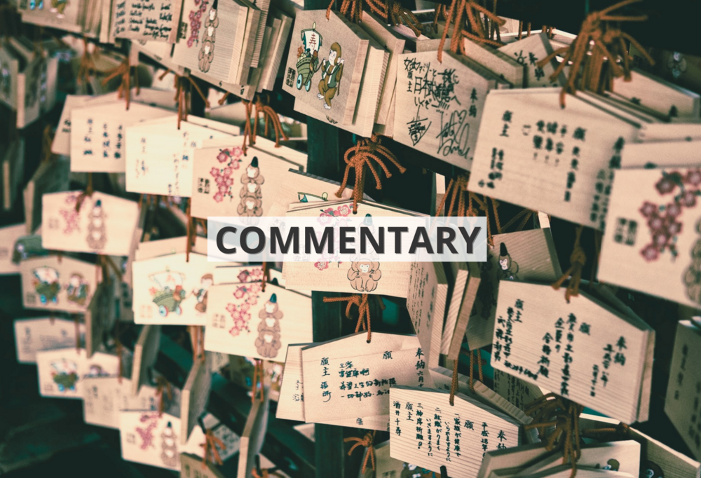 [Translate to English:] Drewniane tabliczki z życzeniami zapisanymi chińskimi znakami wiszące we wschodnioazjatyckiej świątyni z napisem ‘commentary’ / Wooden signs with wishes written in Chinese characters hanging in an East Asian temple with the inscription 'commentary'